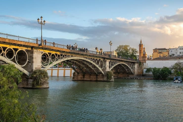 Le pont de Triana est un pont emblématique qui traverse le fleuve Guadalquivir à Séville. Il relie le quartier de Triana, situé à l'ouest du fleuve, au centre historique de Séville, à l'est.